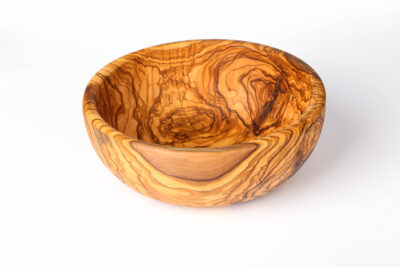 Big wood salad bowl made from finished olive wood used for serving fresh salad on dining table
