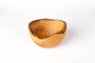 Rustic bowl handcrafted from olive wood displayed on wooden dining table