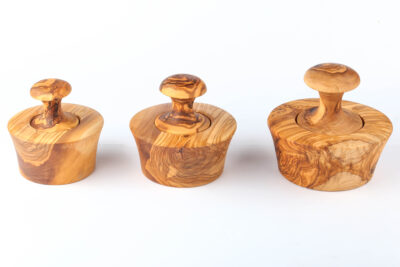 olive wood pestle crushing fresh garlic in deep round bowl